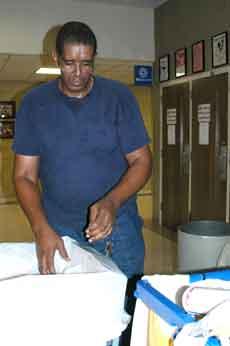 Tyrone Mack, janitor on the first floor of Talbot Hall, replaces a bag inside a trash can for the building.  