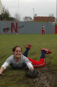Lacy Gros, sophomore pitcher, practices diving for softballs during Fridays practice  at the softball field as sophomore outfielder Danielle Clayton waits for her turn.