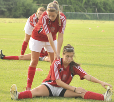 Carolyn Noble, on ground, gets stretched out by a teammate before practice. The Lady Colonels were defeated in their first game against the Eagles of Southern Mississippi with a score of 6-0.