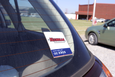A vehicle displays a parking decal placed on top of other decals, a violation of the parking manual.