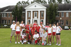 Representatives from each campus sport pose for a photo in front of Elkins Hall.