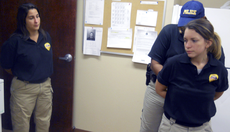 Officer Monica Yates with University Police watches Tuesday as fellow officers Christy Hawxhurst and Heather Boudreaux demonstrate the handcuffing technique used by the department.