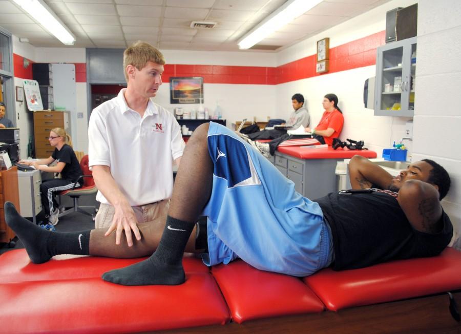 Head athletic trainer Shaun Duhe talks to junior basketball guard Fred Hunter about stretching techniques Tuesday at the athletic training department in Barker Hall.