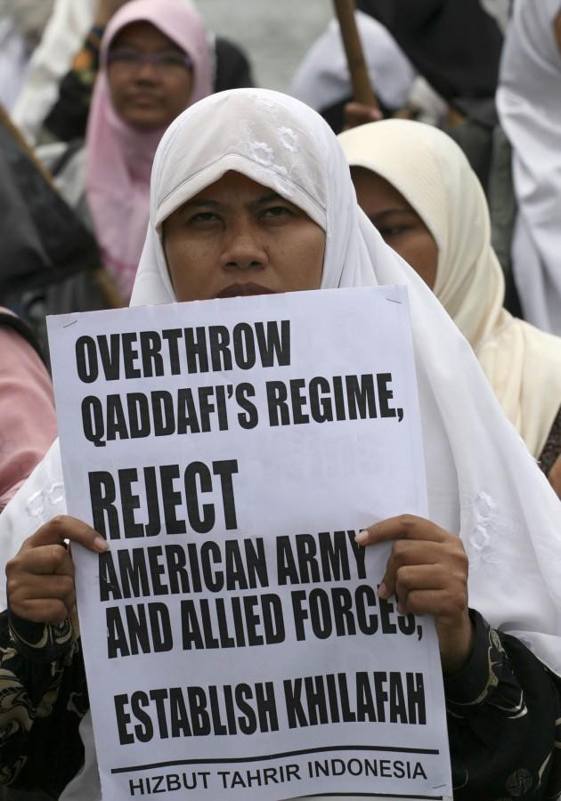 A protester of the hard-line Islamic group Hizbut Tahrir holds an anti-Libyan leader Moammar Gadhafi banner during a solidarity protest in Jakarta, Monday.