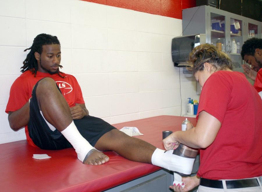 Athletic trainer Laura St. Pierre, senior from Houma, tapes freshman wide receiver Tyrie Allen’s feet at the athletic training department in Barker Hall on Monday before football practice.