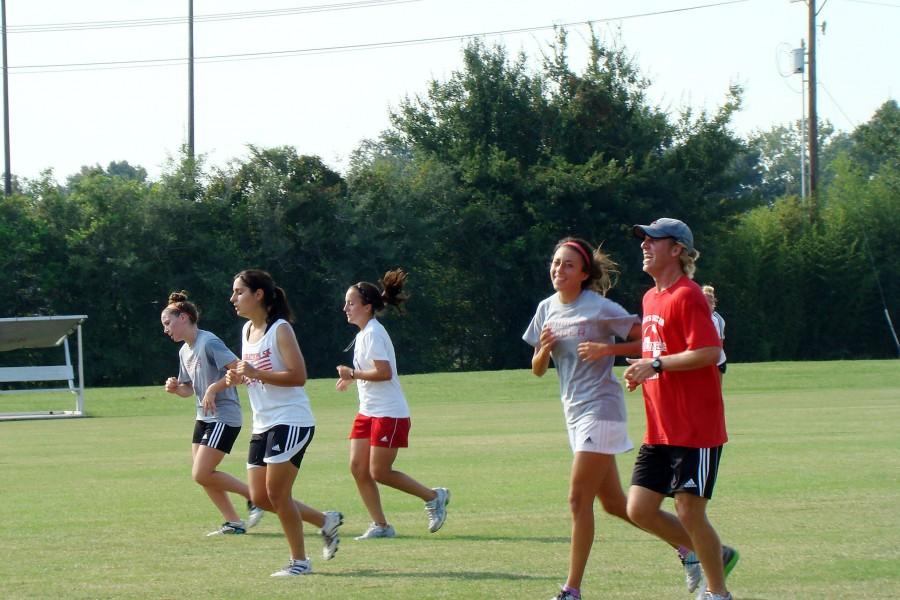 +The+womens+soccer+team+runs+along+side+coach+Dylan+Harrison+at+Mondays+practice.%09+