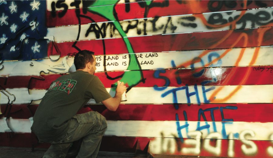 Nicholls art senior Stephen Marcel, from Houma, spray paints on Ira Hill’s American Flag Sculpture.
