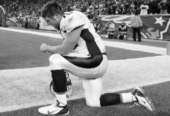 Denver Broncos quarterback Tim Tebow kneels on the sidelines before an NFL divisional playoff football game against the New England Patriots Saturday, Jan. 14, 2012, in Foxborough, Mass.