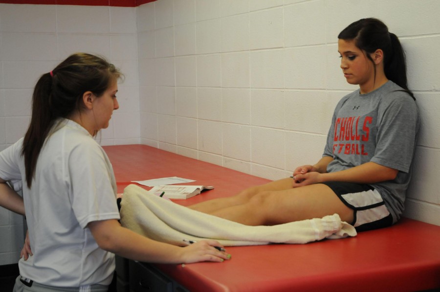 Shellie Pellegrin and Danielle Adam, athletic training juniors from Houma, evaluate Priscilla Burns’ ACL injury on Feb. 28 while Burns stretches.