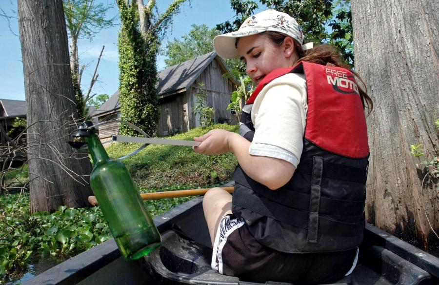 Jerilyn Seguin, marine biology freshman from Metairie, retrieves a glass bottle from Bayou Lafourche on March 31, 2012 during a cleanup organized by the Barataria-Terrebonne National Estuary Program.