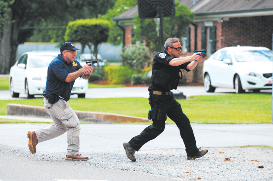 Police officers running to the sound of gun fire during Thibodaux’s city wide emergency drill at E. D. White Wednesday morning.