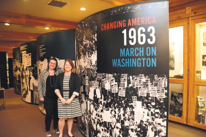Librarians Sarah Simms (left) and Hayley Johnson (right) pose in front of a part of the exhibit “Changing America: The Emancipation Proclamation, 1863 and the March on Washington, 1963.