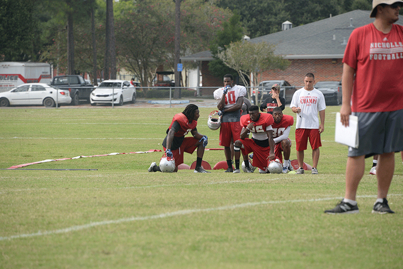 Wide receiver C.J. Bates, junior, takes a knee with his teammates at practice on Tuesday, Sept. 1.