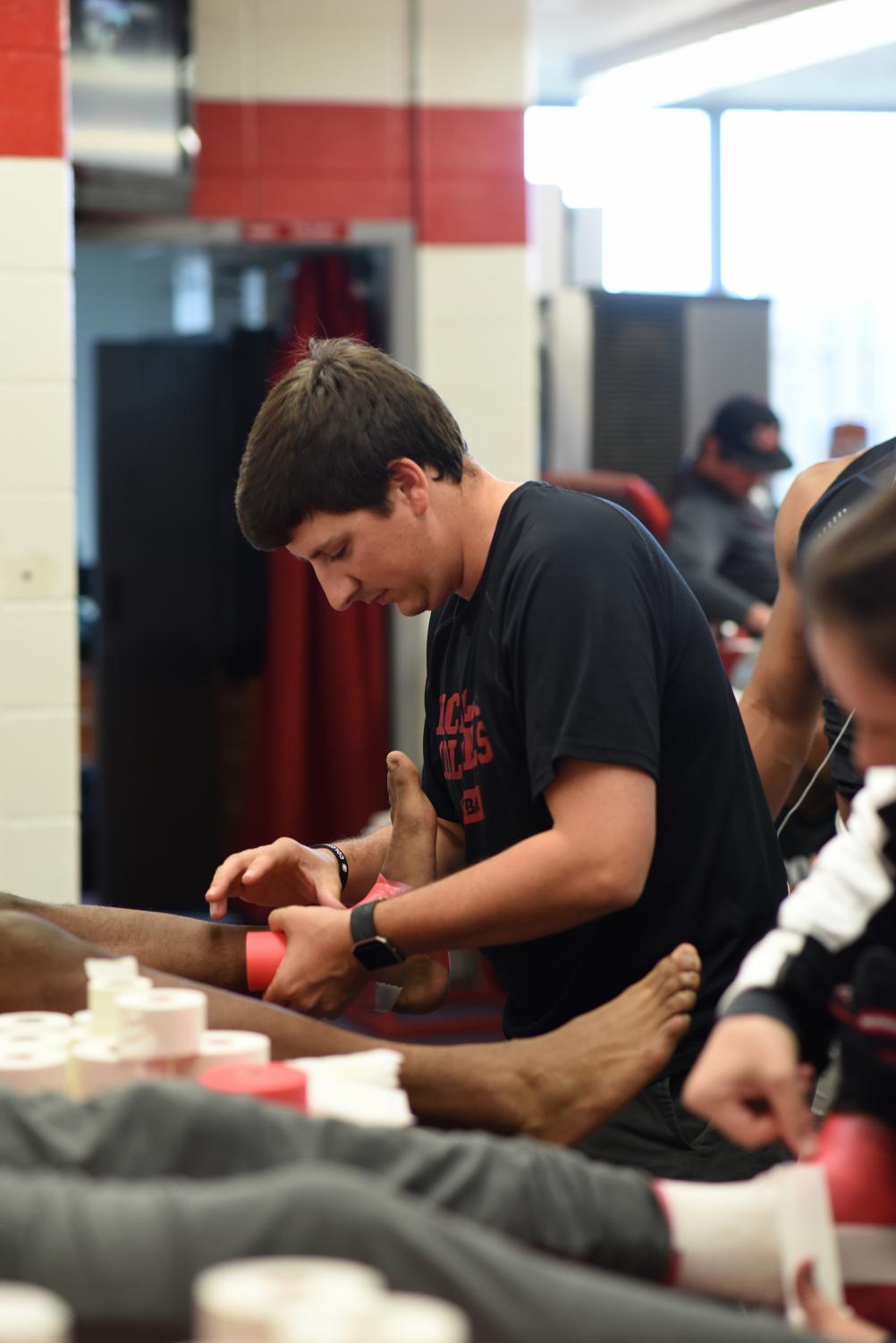 Evan Dauterive, head athletic trainer, wraps a Colonel football player's ankle before practice on Wednesday, March 14.