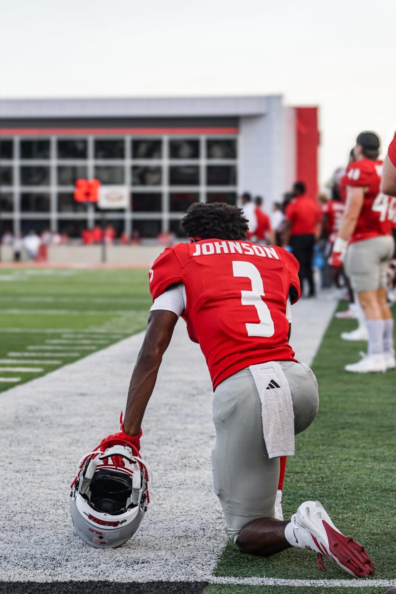 John Carrington III takes a knee on the sidelines.