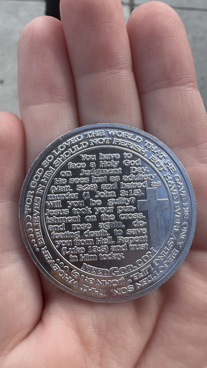 Silver coin bearing an inscription of the Ten Commandments handed out by anti-abortion activist David in front of the Nicholls Student Union.