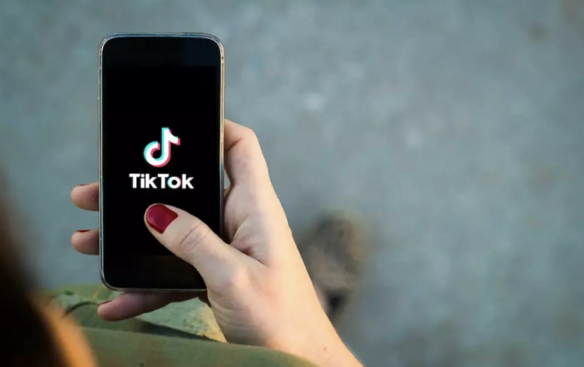 Woman opening TikTok on her iPhone. (Photo via: WAYA Media).