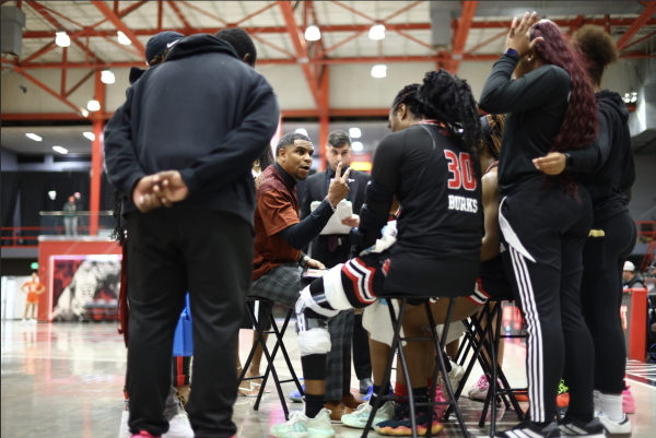 Coach Justin Payne stands in the center of a Nicholls women's basketball team huddle. (Photo via: Anyra Wilson).